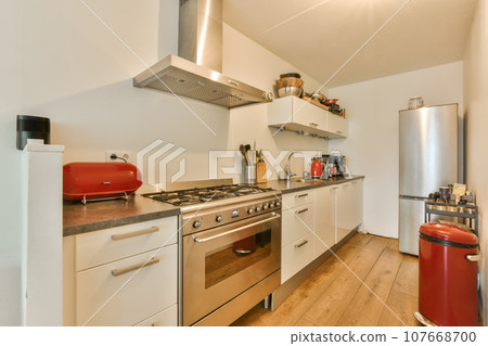 a kitchen with wood flooring and white cupboards on the wall behind it is a stove, dishwasher and refrigerator a kitchen with wood flooring and white cupboards on the wall behind it is a stove, dishwasher and refrigerator 107668700