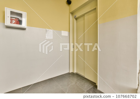a room with yellow walls and grey flooring, including a white wall mounted air conditioning unit on the right side a room with yellow walls and grey flooring, including a white wall mounted air conditioning unit on the right side 107668702