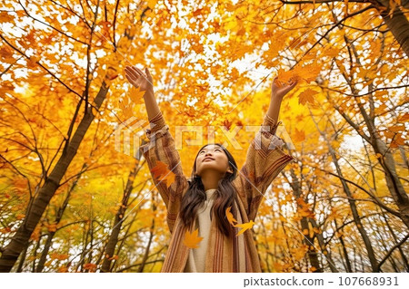 a woman throwing autumn leaves in the air with her arms wide shot on an autumn day 107668931