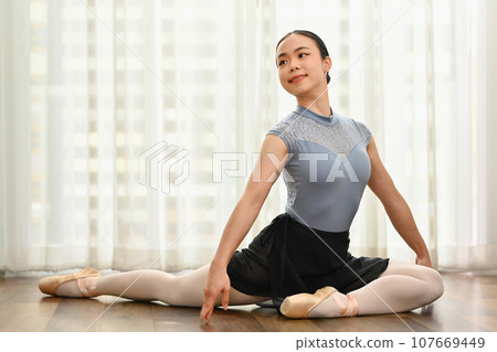 Dedicated Young ballerina in pointe shoes doing stretching exercise on the floor. Classical dance, choreography and art concept Dedicated Young ballerina in pointe shoes doing stretching exercise on the floor. Classical dance, choreography and art concept 107669449
