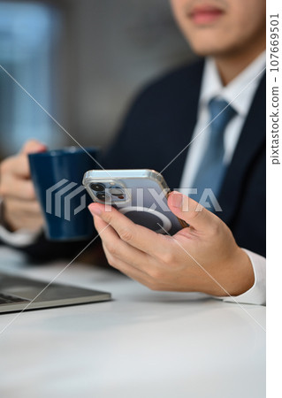 Select focus on businessman using smartphone texting messages, chatting in social during coffee break 107669501