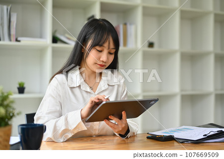 Pretty asian female office worker using digital tablet at her workplace 107669509