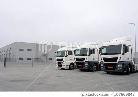 Trucks stand in a row at a truck stop. Cargo semi-trailers for delivery and loading of cargo, logistics, cargo transportation. Car service and truck maintenance Trucks stand in a row at a truck stop. Cargo semi-trailers for delivery and loading of cargo, logistics, cargo transportation. Car service and truck maintenance 107669842