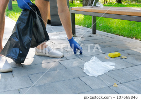 Hand puts plastic trash bottle into black trash bag. Environmental problems, environmental pollution Hand puts plastic trash bottle into black trash bag. Environmental problems, environmental pollution 107669846
