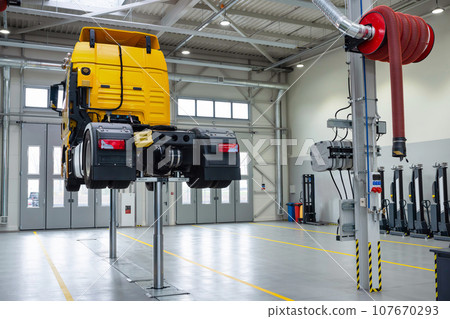Truck on a lift in a car service. Servicing and repairing trucks in a large garage. Dump trucks and trucks in the hangar for diagnostics 107670293
