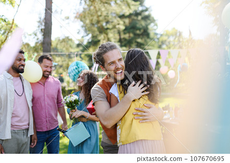 Friends reunite after a long time apart. Men and women embracing, happy to meet at garden party. Friends reunite after a long time apart. Men and women embracing, happy to meet at garden party. 107670695