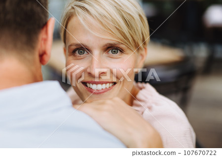 Portrait of beautiful couple in restaurant, on romantic date. Wife and husband touching foreheads, having romantic moment at restaurant patio. 107670722