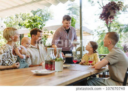 Waiter bringing food to the table in the restaurant. 107670740