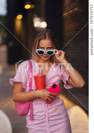 Gen Z girl in pink outfit before going the cinema to watch movie. The young zoomer girl watched movie addressing the topic of women, her position in world, and body image. Gen Z girl in pink outfit before going the cinema to watch movie. The young zoomer girl watched movie addressing the topic of women, her position in world, and body image. 107670757