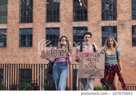 Generation Z activists with banners protesting on the street. Young students marching through the city demonstrate against climate change. Protesters demanding gun control, racial and gender equity. Generation Z activists with banners protesting on the street. Young students marching through the city demonstrate against climate change. Protesters demanding gun control, racial and gender equity. 107670861