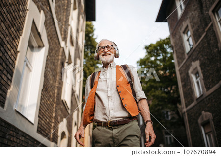 Senior man on the street. Elderly cool man listening to music outdoors, having fun. Concept of old man young at heart. 107670894