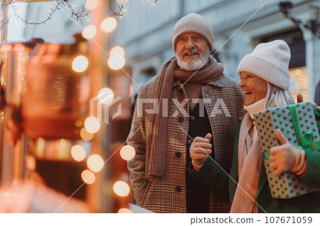 Happy senior couple enjoying christmas market, buying gifts. Happy senior couple enjoying christmas market, buying gifts. 107671059