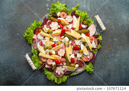 Fiambre, salad of Guatemala, Mexico and Latin America, served on large plate top view. Festive dish for All Saints Day (Day Of The Dead) celebration made of cold cuts, sausages, pickled vegetables 107671124