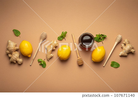Composition with lemons, mint, ginger, honey in glass jar and honey wooden dippers top view. Food for immunity stimulation and against seasonal flu. Healthy natural remedies to boost immune system 107671140