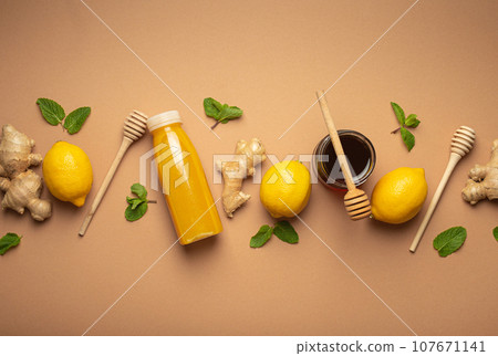 Composition with detox drink, lemons, mint, ginger, honey in glass jar and honey wooden dippers top view. Food for immunity stimulation and against flu. Healthy natural remedies to boost immune system 107671141