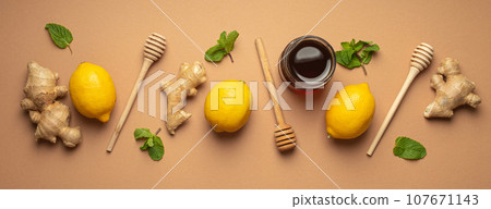 Composition with lemons, mint, ginger, honey in glass jar and honey wooden dippers top view. Food for immunity stimulation and against seasonal flu. Healthy natural remedies to boost immune system Composition with lemons, mint, ginger, honey in glass jar and honey wooden dippers top view. Food for immunity stimulation and against seasonal flu. Healthy natural remedies to boost immune system 107671143