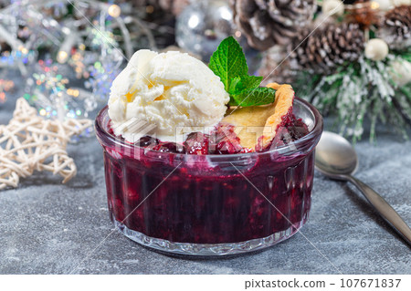 Berry cobbler in glass ramekin with ice cream, Christmas decoration, horizontal 107671837