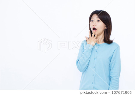 A woman in her thirties who is surprised in front of a white background 107671905