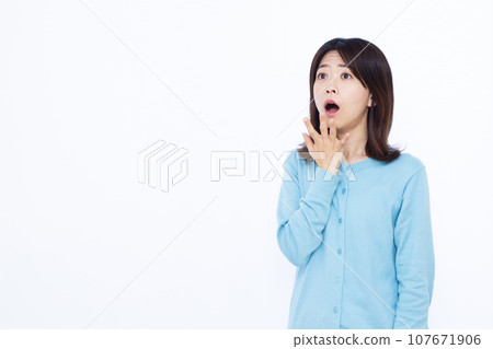 A woman in her thirties who is surprised in front of a white background 107671906