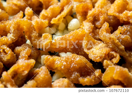 Leftover fried food remake image. A cooking scene where fried chicken skin is stir-fried with garlic. 107672110