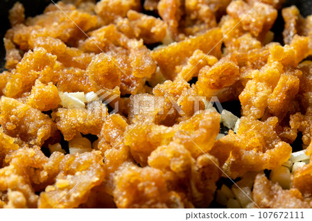 剩下的油炸食品翻拍圖。炸雞皮和大蒜一起炒的烹飪場景。 剩下的油炸食品翻拍圖。炸雞皮和大蒜一起炒的烹飪場景。 107672111