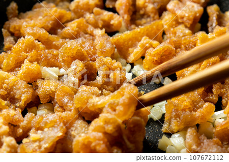 Leftover fried food remake image. A cooking scene where fried chicken skin is stir-fried with garlic. 107672112