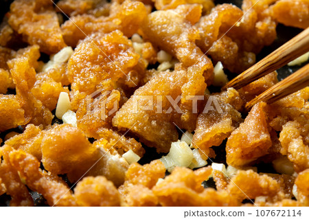 剩下的油炸食品翻拍圖。炸雞皮和大蒜一起炒的烹飪場景。 107672114