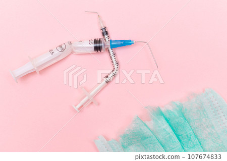 Broken Medical Syringe and Torn Medical Face Mask on the Pink Background 107674833