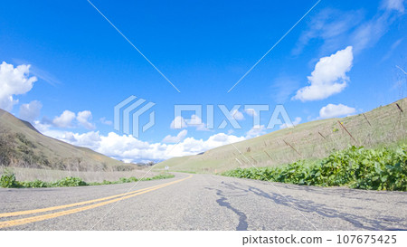 Vehicle is cruising along the Cuyama Highway under the bright sun. The surrounding landscape is illuminated by the radiant sunshine, creating a picturesque and inviting scene as the car travels Vehicle is cruising along the Cuyama Highway under the bright sun. The surrounding landscape is illuminated by the radiant sunshine, creating a picturesque and inviting scene as the car travels 107675425
