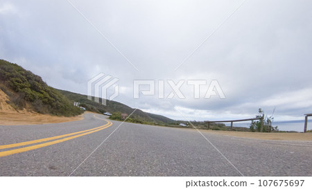In this serene winter scene, a vehicle carefully makes its way along Los Osos Valley Road and Pecho Valley Road within Montana de Oro State Park. In this serene winter scene, a vehicle carefully makes its way along Los Osos Valley Road and Pecho Valley Road within Montana de Oro State Park. 107675697