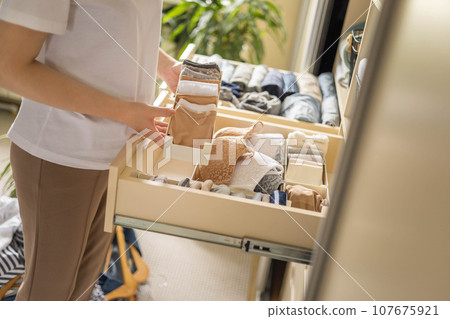 Women's hands close up. Boxes for underwear. Concept of closet organization and storage of socks and underwear. 107675921