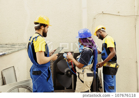 Competent mechanics diverse team hired by client to search for refrigerant leaks on outdoor air conditioner evaporator coil leading to poor cooling issues during hot summer months Competent mechanics diverse team hired by client to search for refrigerant leaks on outdoor air conditioner evaporator coil leading to poor cooling issues during hot summer months 107676118