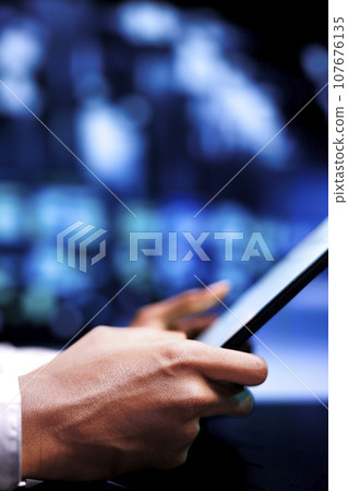 Certified serviceman resolving performance related issues in server hub. Technician utilizing mock up tablet to identify operational problems causing supercomputer slowdown 107676135