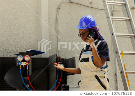 African american apprentice calling manager to inquire about necessary condenser components needing to be replaced. Electrician checking maintenance plan after fixing bad wiring issues African american apprentice calling manager to inquire about necessary condenser components needing to be replaced. Electrician checking maintenance plan after fixing bad wiring issues 107676138