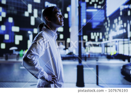 Asian man wandering around city boulevards during nighttime, being amazed by urban landscape buildings. Citizen strolling around empty avenues at night, enjoying street lamps illuminated surroundings Asian man wandering around city boulevards during nighttime, being amazed by urban landscape buildings. Citizen strolling around empty avenues at night, enjoying street lamps illuminated surroundings 107676193