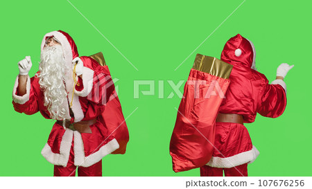 Saint nick bandmaster chief in costume accompany professional orchestra as choir musician, standing over greenscreen. Santa claus with gifts bag playing band music, musical conductor. 107676256
