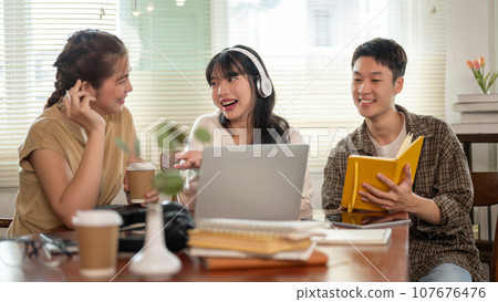 A group of cheerful Asian college students are enjoying talking and discussing their group project. 107676476