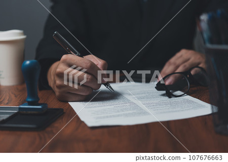Businessman holding a pen signing a document, law ,job search, write a personal contract on desk. Businessman holding a pen signing a document, law ,job search, write a personal contract on desk. 107676663