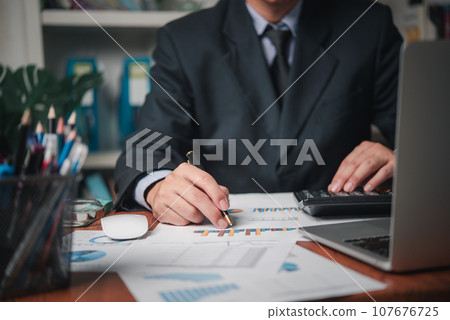 businessman working accountant document graph and chart on desk using calculator for calculate finance report in office. 107676725