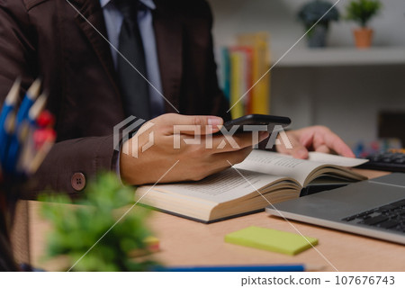 Man using smartphone digital devices reading a book workstation digital technology and reading habits knowledge. Education concept. 107676743