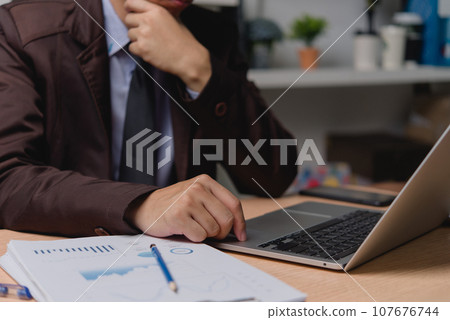 Businessman hands typing on keyboard working at desk. Business reports analyzing financial and marketing graphs document and charts data analysis office workspace. 107676744