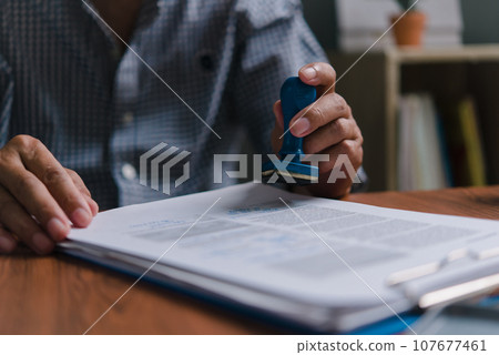 Businessman stamping with approved stamp on document contract. Business marketing investment of information law concept. Businessman stamping with approved stamp on document contract. Business marketing investment of information law concept. 107677461