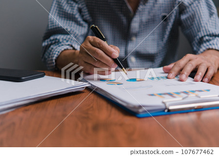 Businessman analyzing business planning, strategy, marketing and financial reports Hand Holding File, Checking reports, and reviewing business statistics. 107677462
