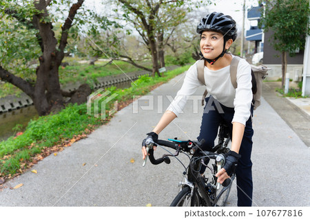 A young woman wearing business casual clothes riding a road bike A young woman wearing business casual clothes riding a road bike 107677816
