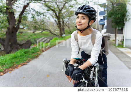 A young woman wearing business casual clothes riding a road bike 107677818