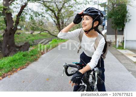 一位穿著商務休閒服騎公路自行車的年輕女子 一位穿著商務休閒服騎公路自行車的年輕女子 107677821