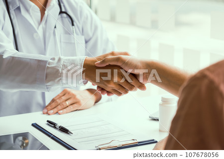 Doctor shaking hands with older patient in the clinic room. 107678056