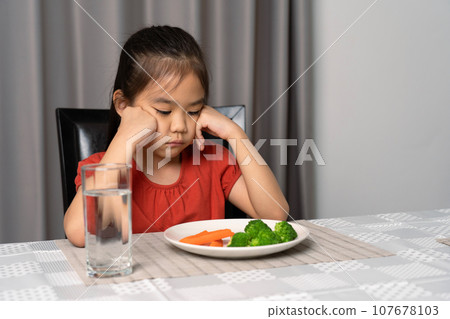 Little cute kid girl refusing to eat healthy vegetables. Children do not like to eat vegetables. Little cute kid girl refusing to eat healthy vegetables. Children do not like to eat vegetables. 107678103
