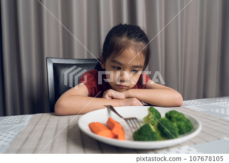 Little cute kid girl refusing to eat healthy vegetables. Children do not like to eat vegetables. Little cute kid girl refusing to eat healthy vegetables. Children do not like to eat vegetables. 107678105