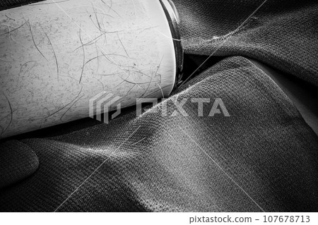 Focus stack of a lint roller resting on a dark suit jacket to remove pet animal hair. 107678713